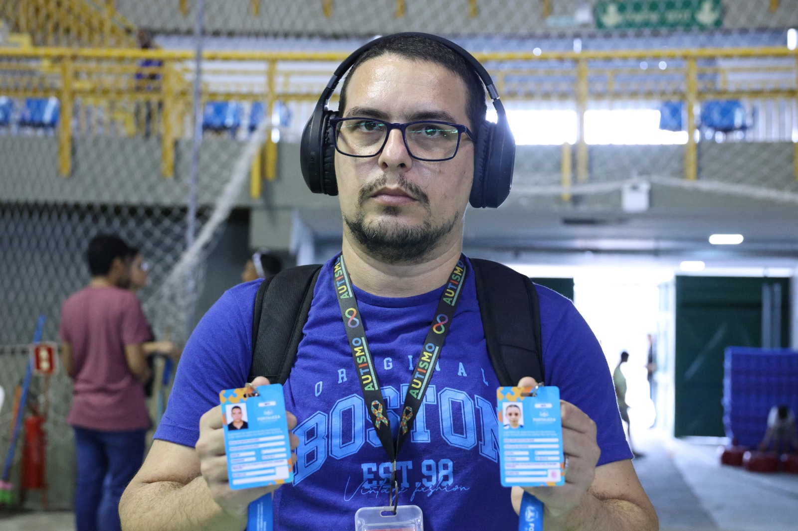 homem posa para a foto usando fones de ouvido e mostrando duas carteirinhas